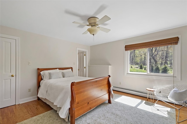 bedroom with baseboards, ceiling fan, a baseboard heating unit, and wood finished floors