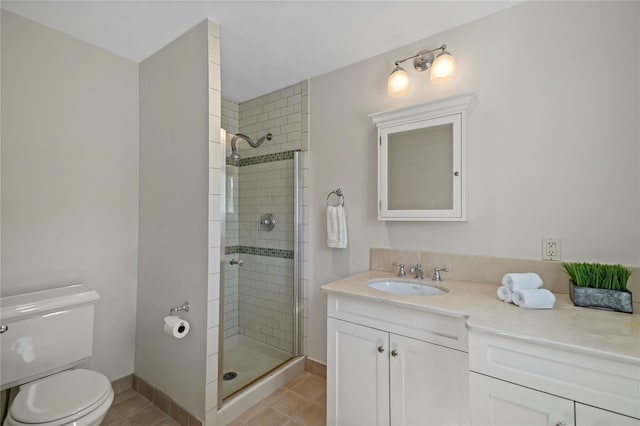 full bathroom featuring tile patterned flooring, a shower stall, vanity, baseboards, and toilet