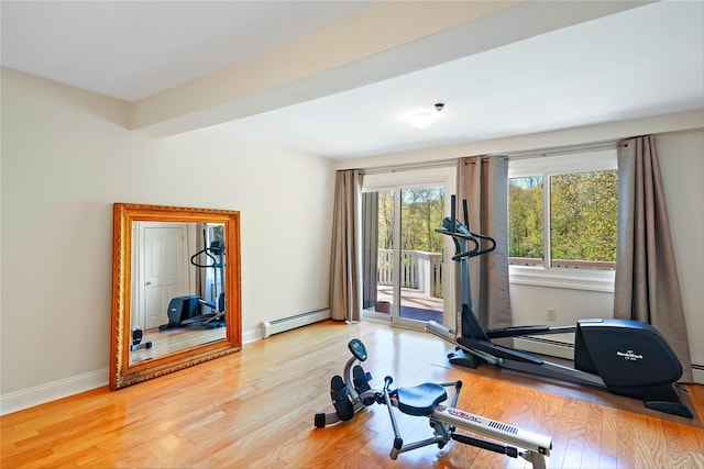 exercise area featuring baseboards, wood finished floors, and baseboard heating