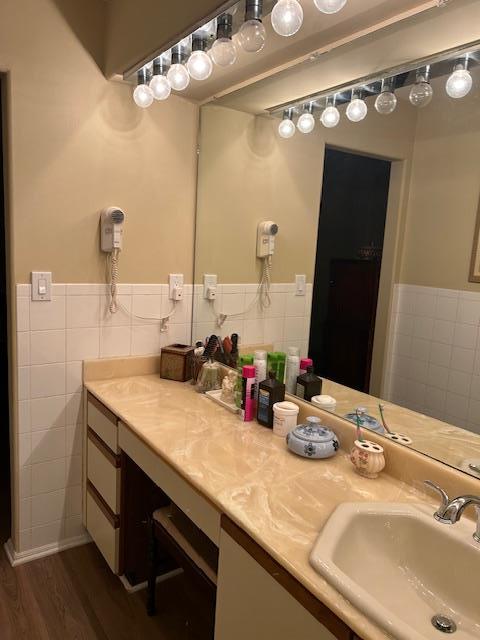 bathroom with a wainscoted wall, tile walls, vanity, and wood finished floors