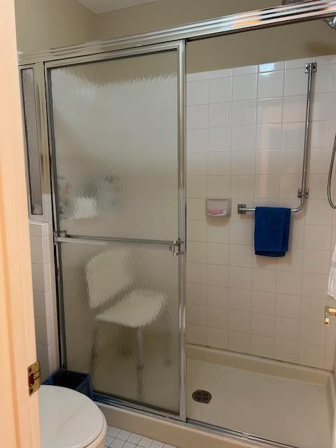 bathroom with tile patterned flooring, a shower stall, and toilet