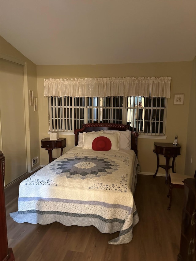 bedroom with lofted ceiling, wood finished floors, visible vents, and baseboards