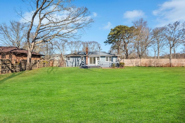 back of house with a fenced backyard and a lawn