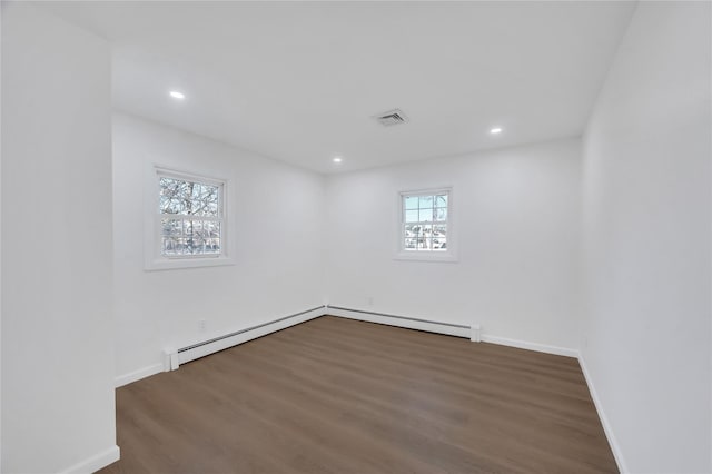 empty room with a baseboard heating unit, plenty of natural light, visible vents, and baseboards