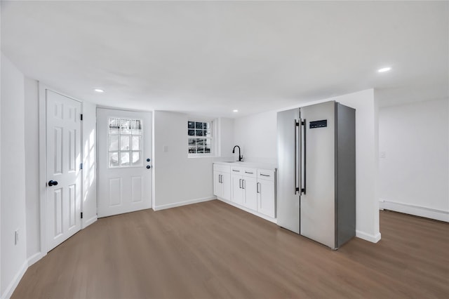 interior space with white cabinets, high quality fridge, wood finished floors, light countertops, and a sink