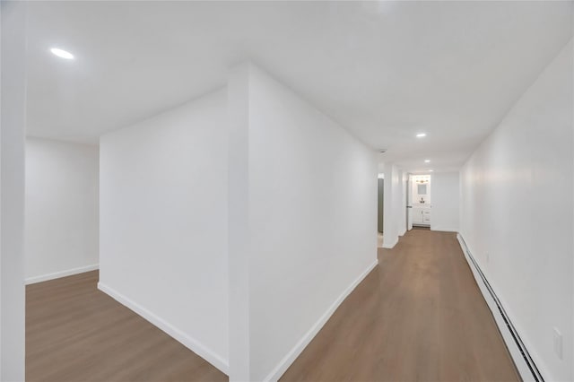 hallway with a baseboard radiator, recessed lighting, baseboards, and wood finished floors