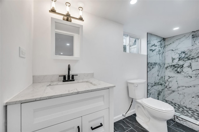 bathroom with toilet, marble finish floor, a tile shower, vanity, and recessed lighting