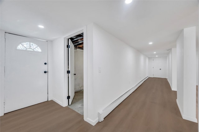 hallway featuring a baseboard heating unit, recessed lighting, baseboards, and wood finished floors