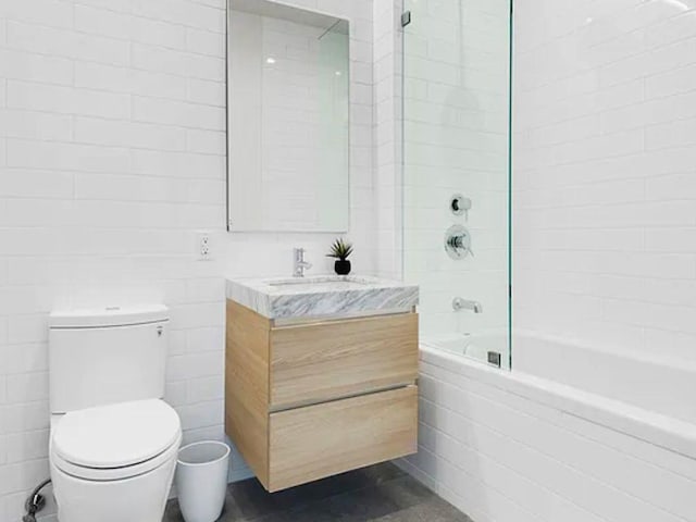 full bath with tile walls, vanity, toilet, and bathing tub / shower combination