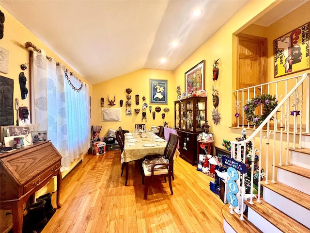 dining area with lofted ceiling, stairway, and wood finished floors