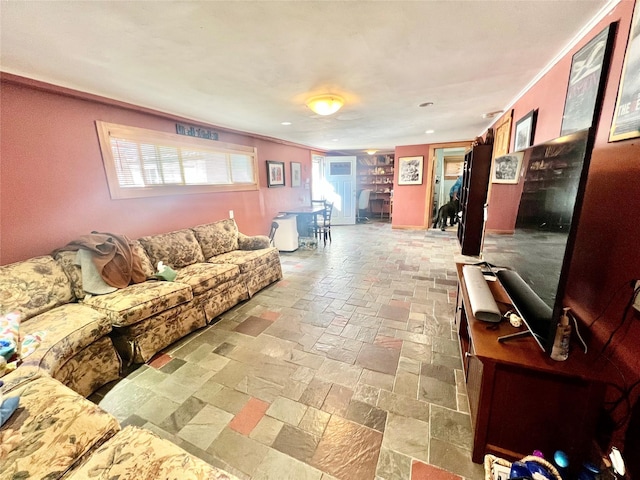 living area featuring stone tile flooring and crown molding