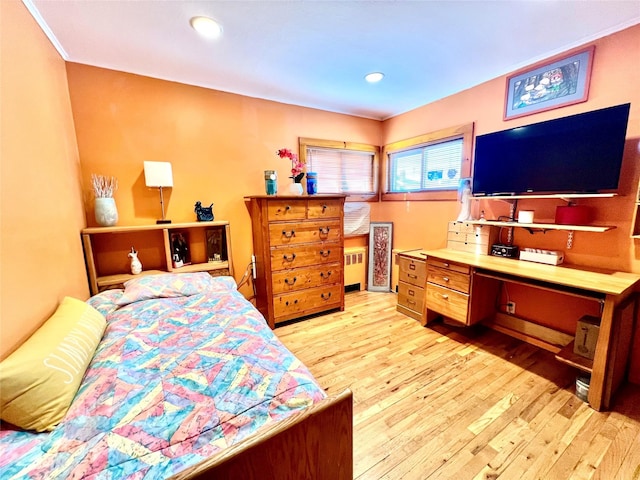 bedroom with radiator heating unit, wood finished floors, and recessed lighting