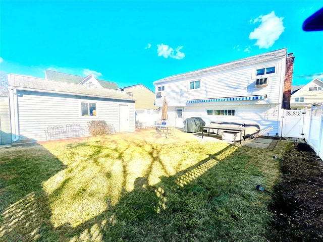 back of property with an outdoor structure, fence, a yard, a gate, and a patio area