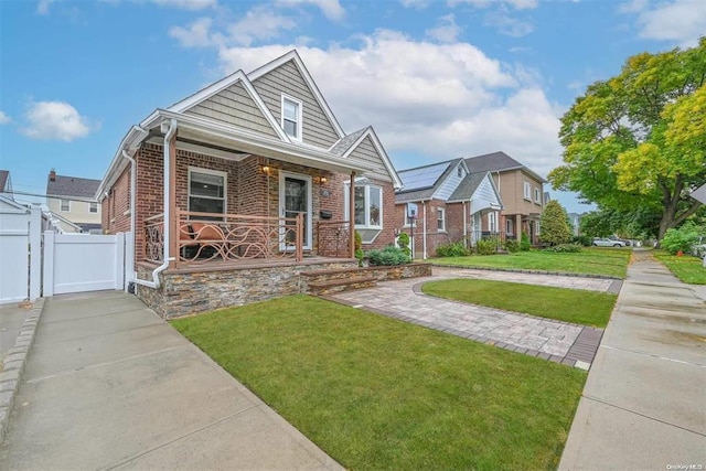 view of front of house featuring a front yard, a residential view, a porch, and brick siding