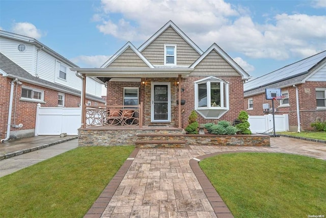 view of front of house with fence, a porch, and brick siding