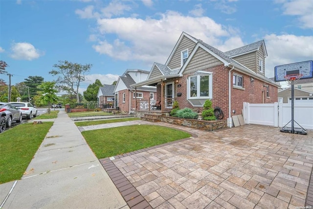 view of front of house with brick siding, fence, and a front lawn