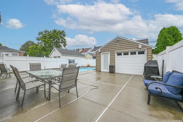 view of patio with a fenced backyard, a garage, a grill, driveway, and outdoor dining space