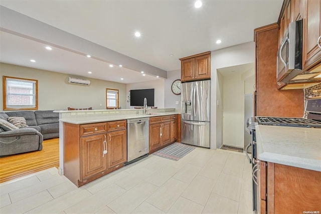 kitchen featuring appliances with stainless steel finishes, open floor plan, light countertops, and a wall mounted AC