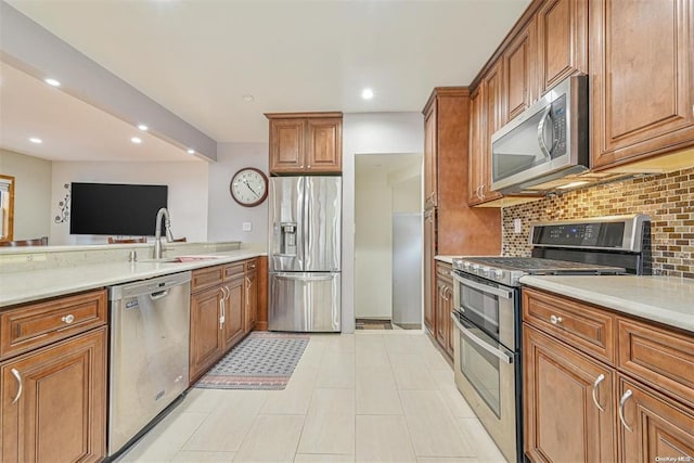 kitchen featuring a sink, stainless steel appliances, brown cabinetry, and light countertops