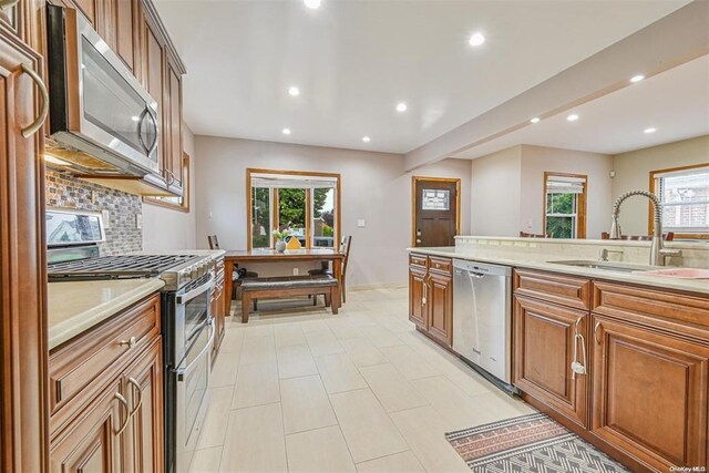 kitchen with appliances with stainless steel finishes, brown cabinets, light countertops, and a sink