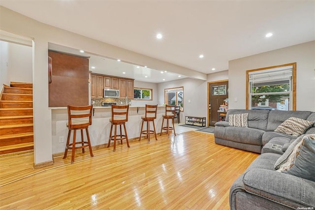 living room featuring recessed lighting, plenty of natural light, light wood-style flooring, and stairs