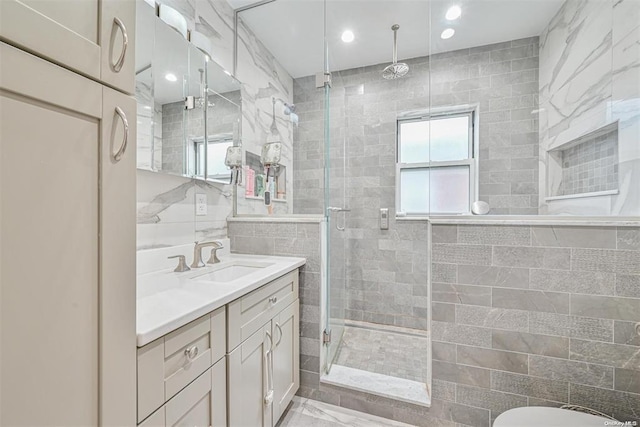 bathroom with recessed lighting, a shower stall, tile walls, and vanity