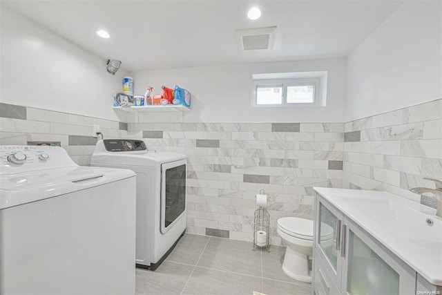 washroom with light tile patterned floors, laundry area, independent washer and dryer, and tile walls