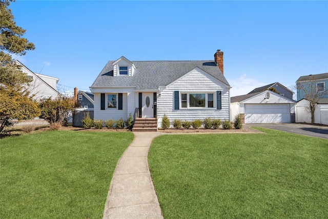 cape cod-style house featuring a shingled roof, a detached garage, a chimney, an outdoor structure, and a front lawn