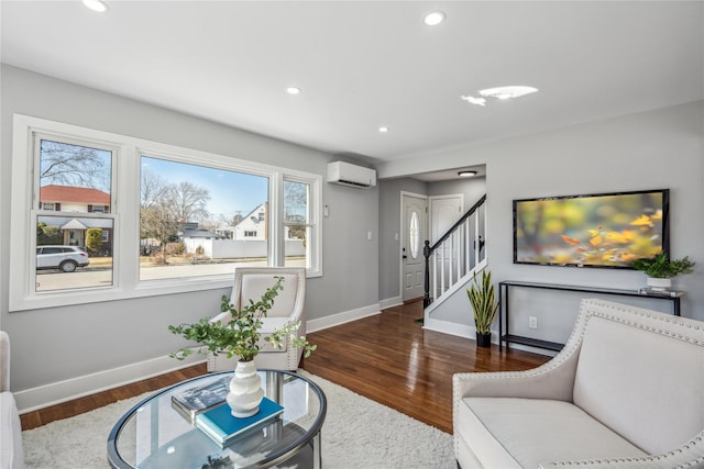 living area with recessed lighting, wood finished floors, baseboards, an AC wall unit, and stairway