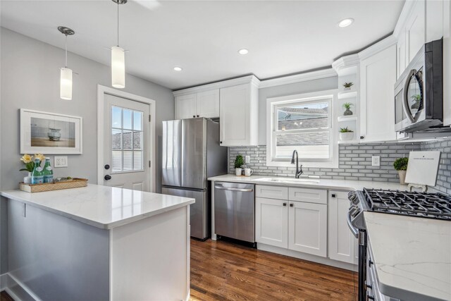 kitchen with dark wood-style floors, light stone counters, stainless steel appliances, white cabinetry, and a sink