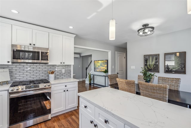 kitchen featuring white cabinets, decorative backsplash, dark wood-style floors, appliances with stainless steel finishes, and pendant lighting