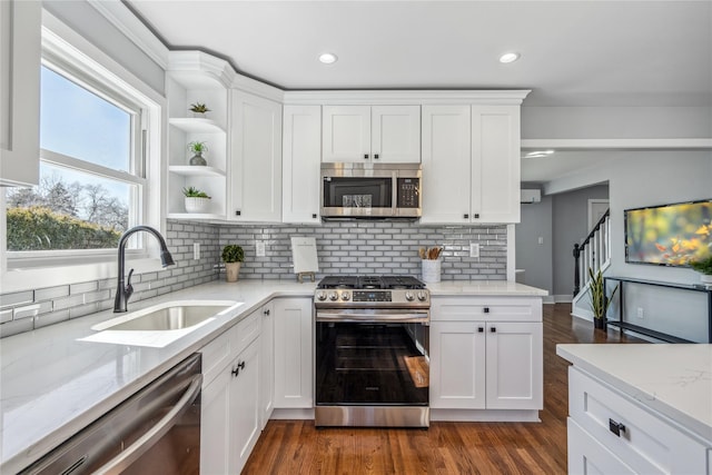 kitchen featuring white cabinets, light stone counters, appliances with stainless steel finishes, dark wood-type flooring, and a sink