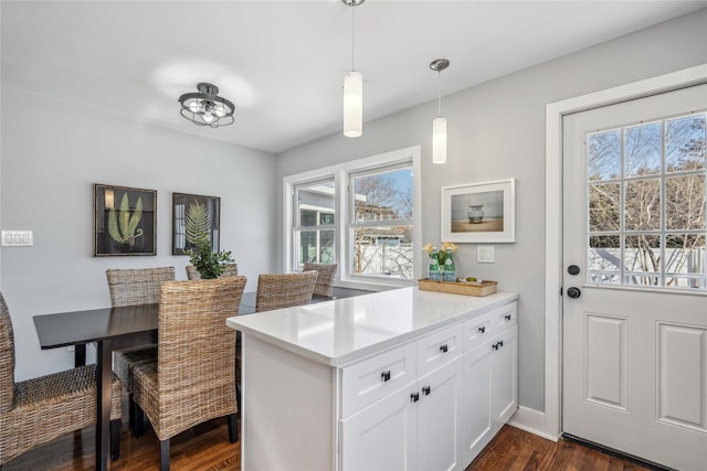 kitchen featuring dark wood-type flooring, a peninsula, hanging light fixtures, light countertops, and white cabinetry