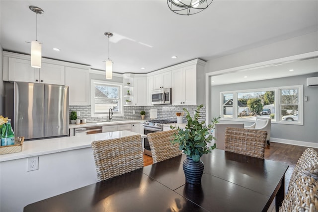 kitchen with a sink, white cabinetry, light countertops, appliances with stainless steel finishes, and backsplash