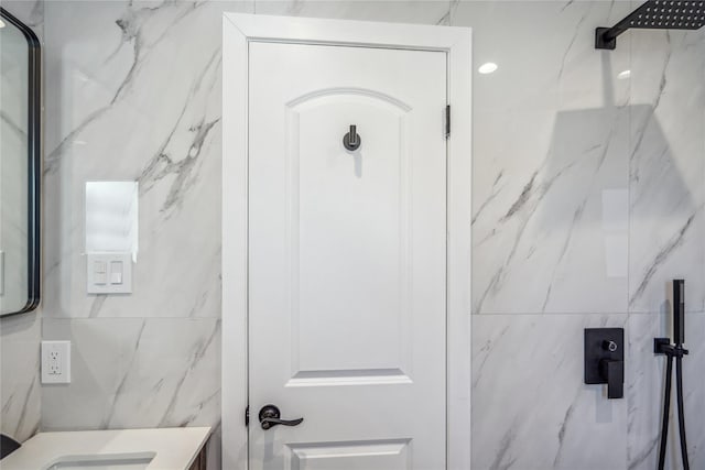 full bathroom with a marble finish shower and vanity