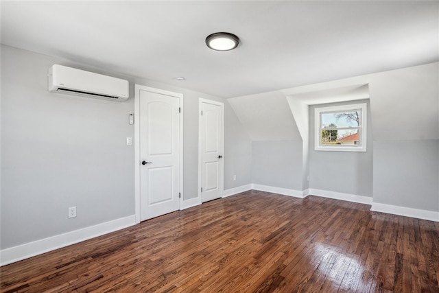 additional living space featuring lofted ceiling, a wall mounted air conditioner, hardwood / wood-style flooring, and baseboards