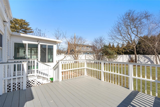 wooden deck with a sunroom, a fenced backyard, and a lawn