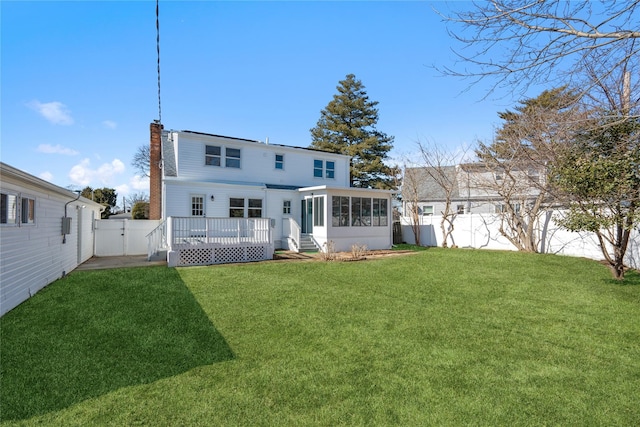 back of house featuring a deck, a lawn, a fenced backyard, and a sunroom