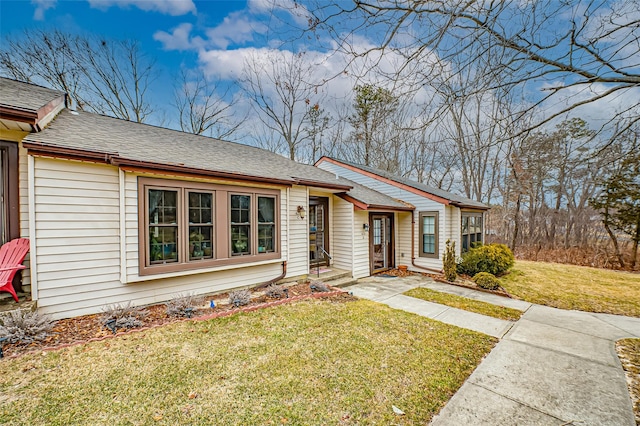 ranch-style home with a shingled roof and a front yard