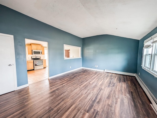 spare room featuring a baseboard heating unit, vaulted ceiling, and light wood-style flooring