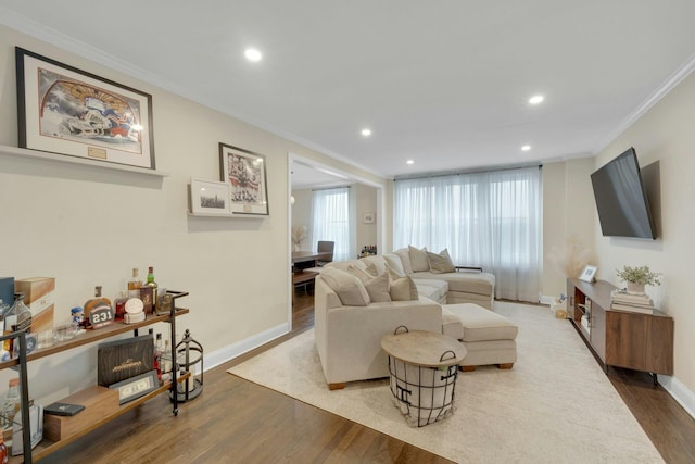 living area featuring baseboards, recessed lighting, wood finished floors, and crown molding