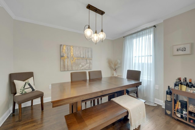 dining room with a notable chandelier, ornamental molding, wood finished floors, and baseboards