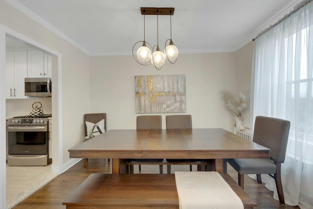 dining room featuring baseboards, a chandelier, crown molding, and wood finished floors