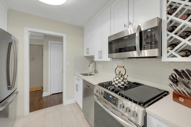 kitchen featuring light countertops, appliances with stainless steel finishes, a sink, and white cabinetry