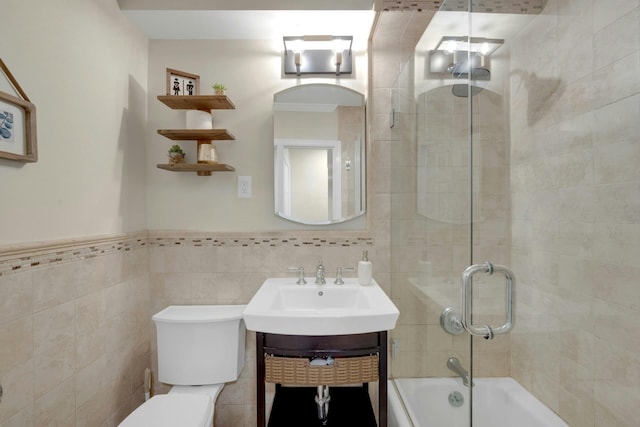 bathroom with shower / bathtub combination, toilet, vanity, tile walls, and wainscoting