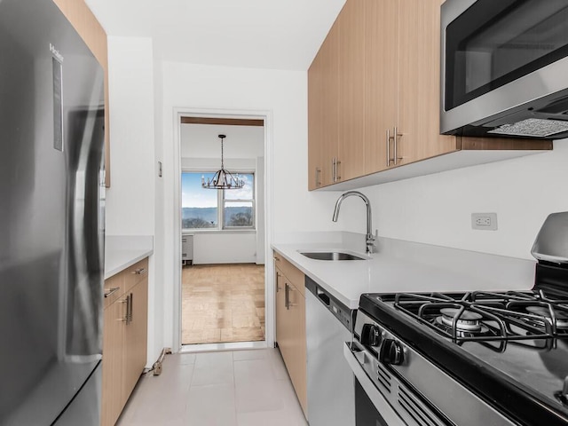 kitchen featuring stainless steel appliances, light countertops, a sink, and light brown cabinets