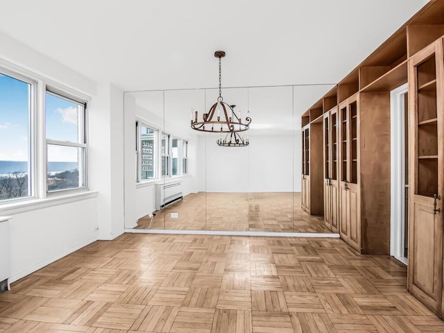 unfurnished dining area featuring a chandelier and radiator