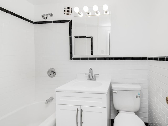 bathroom featuring shower / washtub combination, tile walls, vanity, and toilet