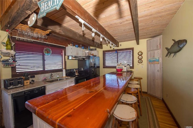 kitchen with a sink, beam ceiling, black appliances, and wooden ceiling