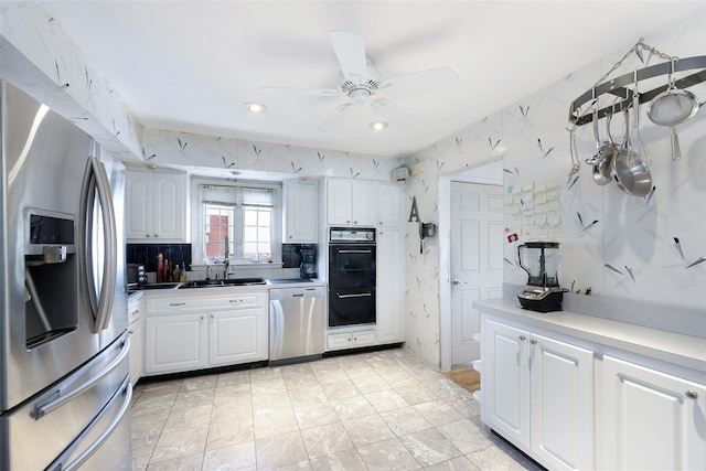 kitchen featuring tasteful backsplash, appliances with stainless steel finishes, white cabinetry, ceiling fan, and a sink